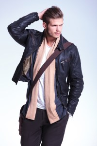 man in leather jacket is looking away to his side and smiles