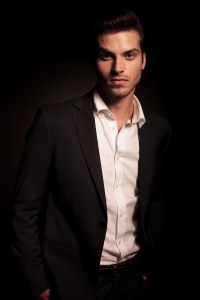 business man with hands in his pockets on dark background